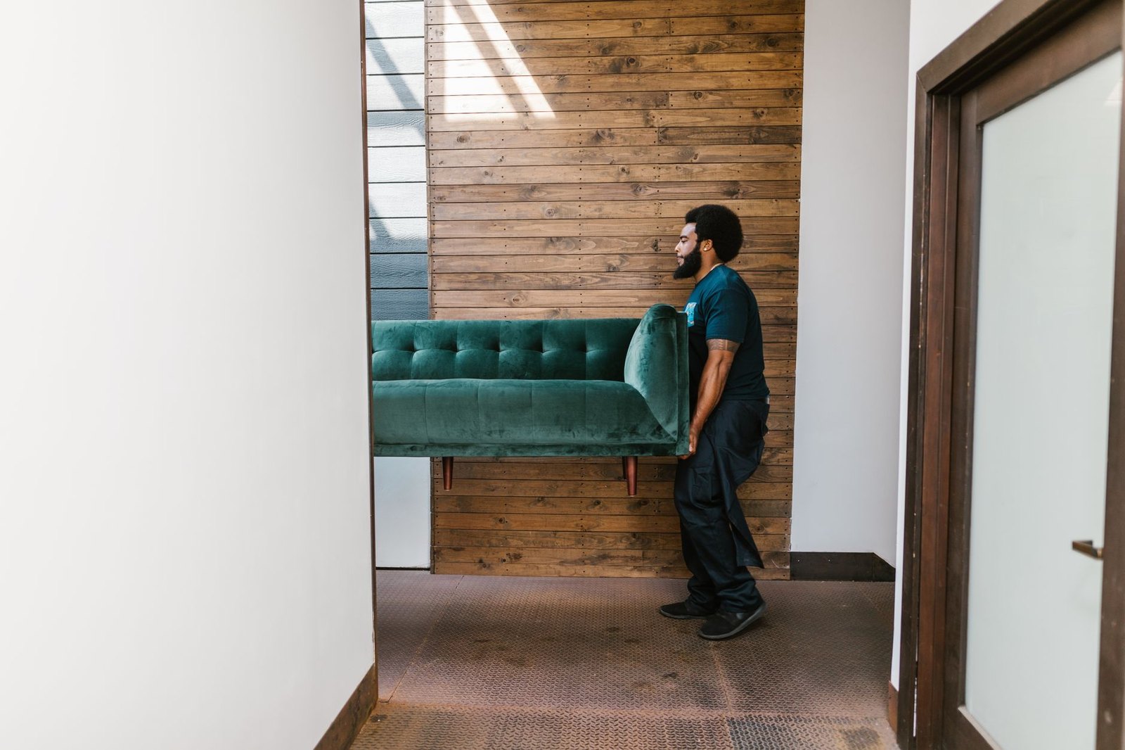 Junk removal worker carrying an old couch out through a doorway during a Vero Beach pickup