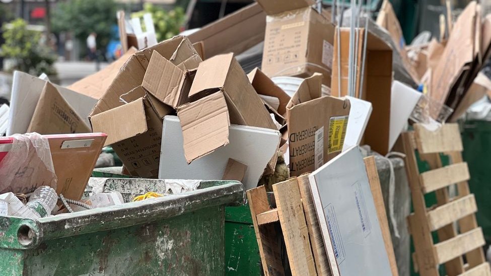 Dumpster piled with broken-down boxes and pallets, the kind of load volume that affects junk removal cost in Vero Beach